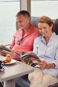 couple sitting and reading magazine in club class onboard condor rapide