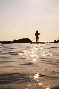 people paddleboarding guernsey on sunlit sea