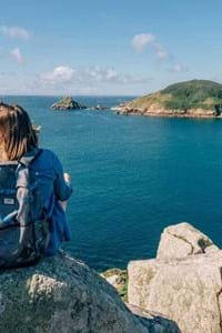 couple sitting on rock looking over guernsey sea channel islands