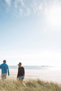 a couple walking through long grass in jersey channel islands